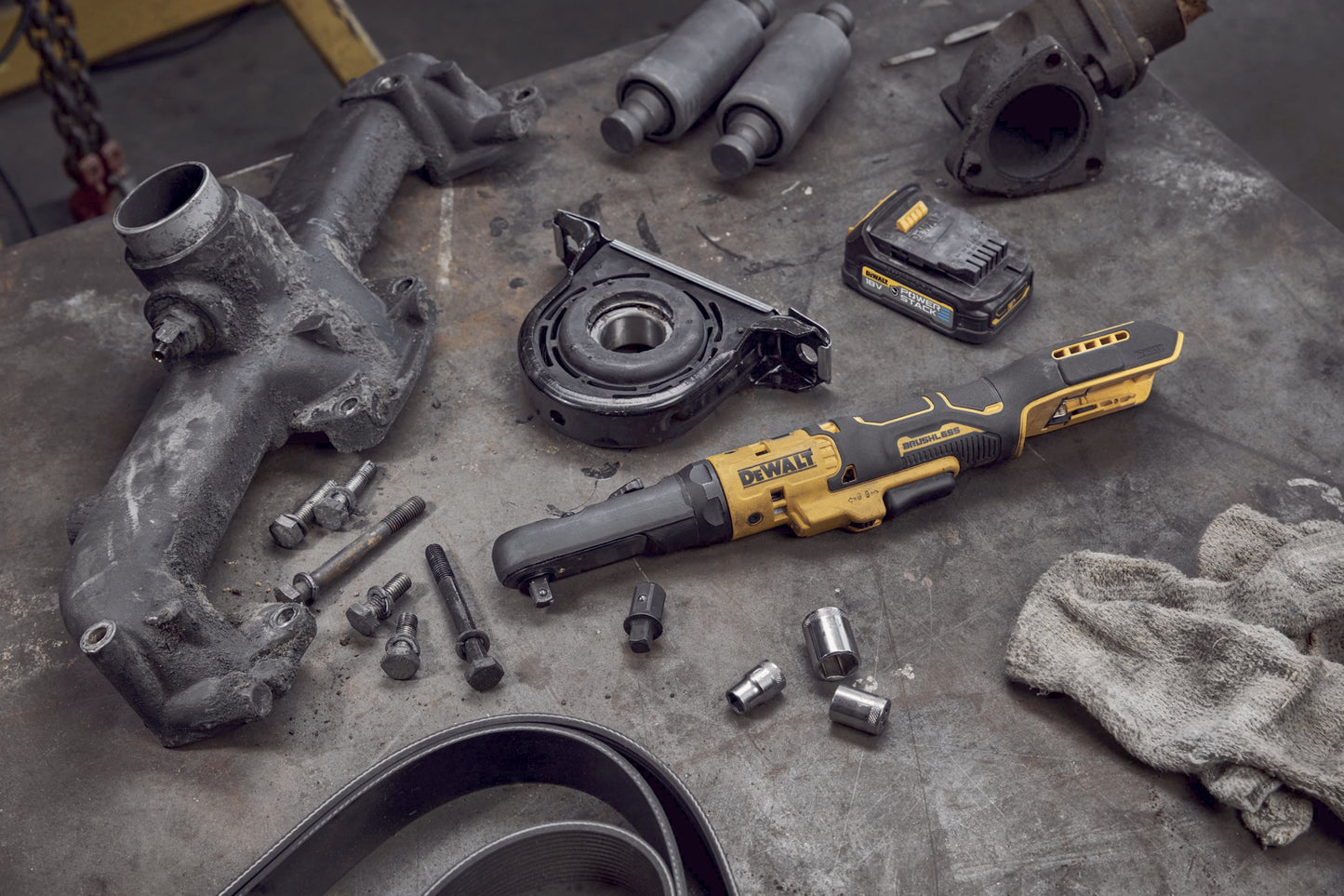 Dewalt DCF510N Akku-Ratsche mit einem Akku liegt auf einer Werkbank neben Motorbauteilen