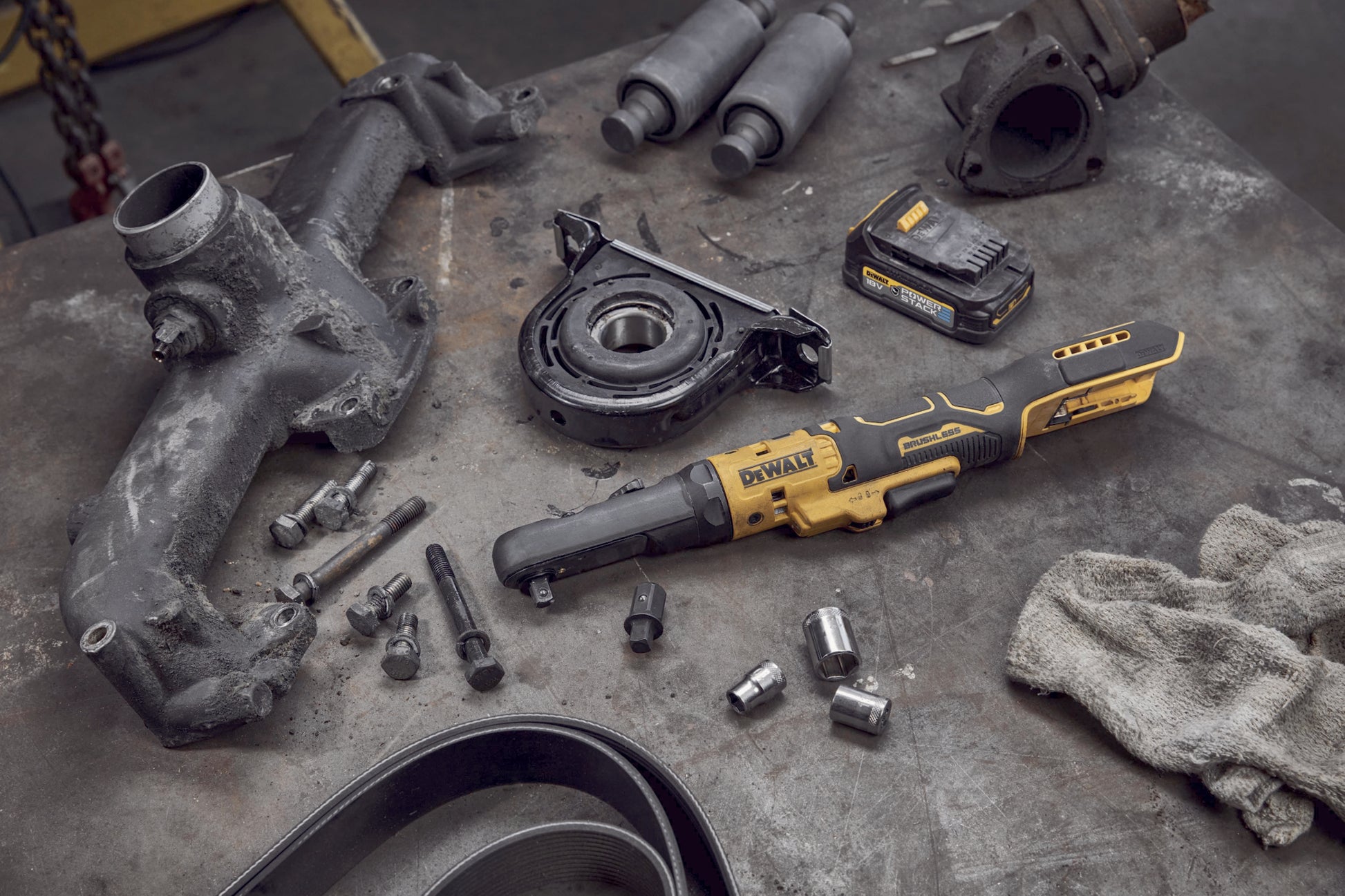 Dewalt DCF510N Akku-Ratsche mit einem Akku liegt auf einer Werkbank neben  Motorbauteilen